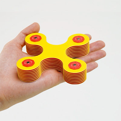 Hand holding a stack of colorful Clixo magnetic pieces to show compact size.